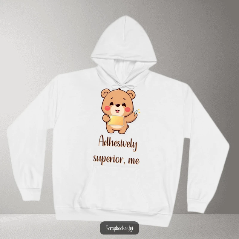 Funny hoodie with a cheerful bear carefully gluing a shiny sticker into place, perfect for cozy crafting and warm vibes.