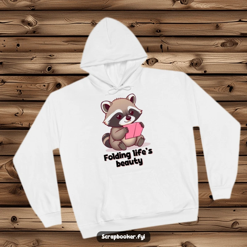 Funny content raccoon folding a vibrant piece of paper, featured on a comfortable and humorous hoodie.